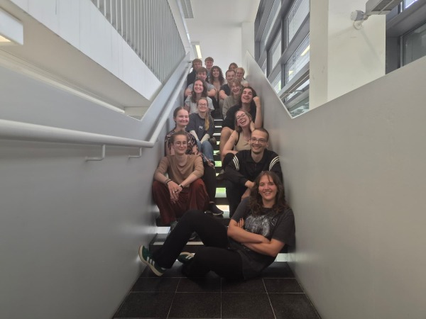 Fachschaftsrat für Naturwissenschaften 2026 Die Mitglieder des neugewählten Fachschaftsrat für Naturwissenschaften sitzen lächelnd auf einer Treppe in Gebäude 22.